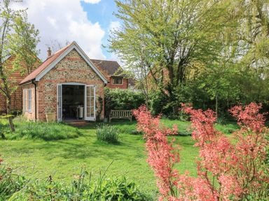 A brick building with open doors in a garden at Bridge Studio Near Broad Chalke