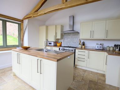 A kitchen with an island sink cooker microwave toaster and wooden countertops at The Old Mill in Flaxley