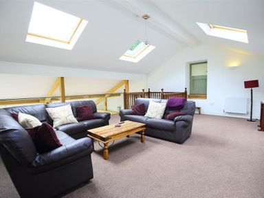 A living room with two leather sofas a wooden coffee table skylight windows and a floor lamp at The Old Mill in Flaxley