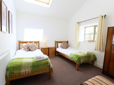 A bedroom with two single beds with green blankets and pillows at The Old Mill in Flaxley