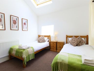 A bedroom with two single beds green throws and wooden headboards and bedside tables at The Old Mill in Flaxley
