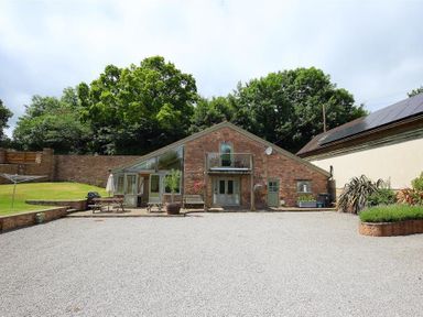 A brick house with gravel driveway picnic tables and trees at The Old Mill in Flaxley