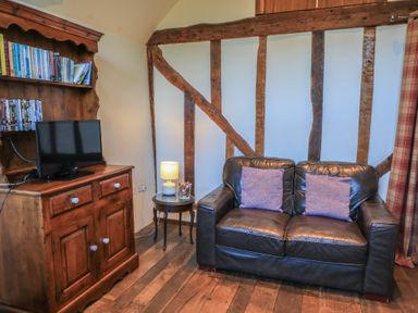A living room with a sofa, television, and bookshelf at Pop's Barn in Downton