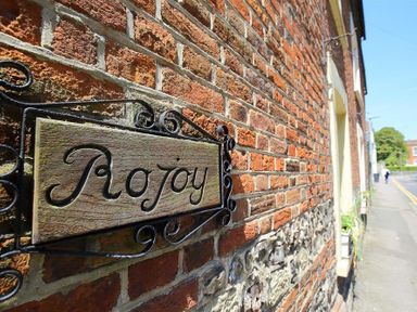 A wooden sign with Rojoy on a brick wall outside a building at Rojoy Salisbury