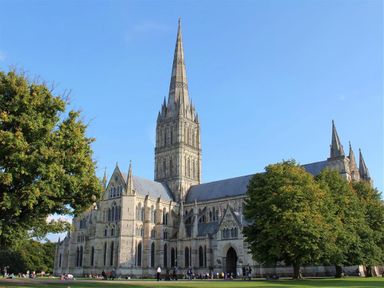 A large cathedral with a tall spire surrounded by trees and grass at Rojoy Salisbury