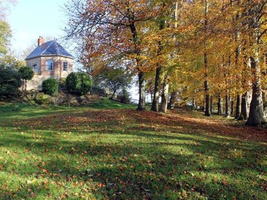A small stone house on a hill surrounded by trees with autumn leaves at The Folly at Castlebridge in Mere