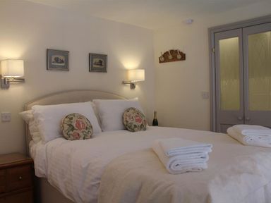 A bedroom with a bed with floral pillows and folded towels on top at The Folly at Castlebridge in Mere