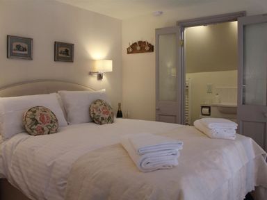 A bedroom with a double bed pillows folded towels and an open door leading to a bathroom at The Folly at Castlebridge in Mere