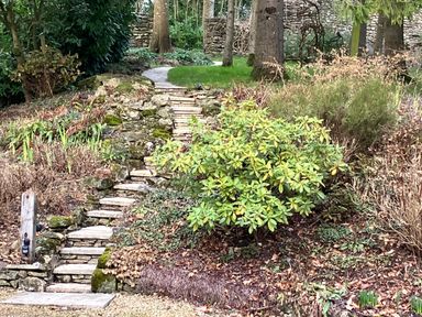 A stone stairway surrounded by plants and trees in a garden at The Folly at Castlebridge in Mere