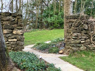 A stone pathway leading between two stone pillars with grass and trees in the background at The Folly at Castlebridge in Mere