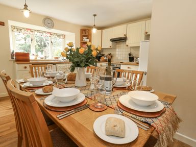 A dining table set with dishes and flowers at Droop Farm Cottage in Droop near Hazelbury Bryan
