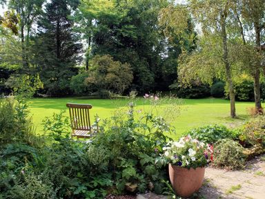 A garden with flowers and a chair at Droop Farm Cottage, Droop near Hazelbury Bryan