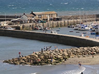 A harbor with boats and people on a rocky shore at Droop Farm Cottage in Droop near Hazelbury Bryan