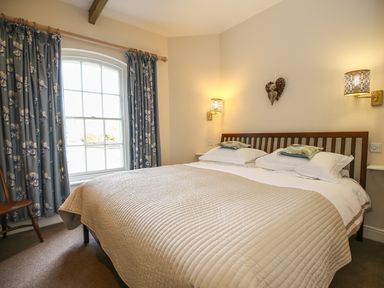A bedroom with a double bed beside a window with floral curtains at West Lodge Rockbourne