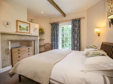 A bedroom with a bed a chest of drawers a window with curtains and a chair at West Lodge in Rockbourne