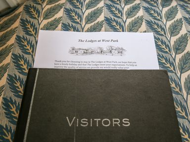 A visitor book and a paper with text on a patterned fabric surface at The Lodges at West Park