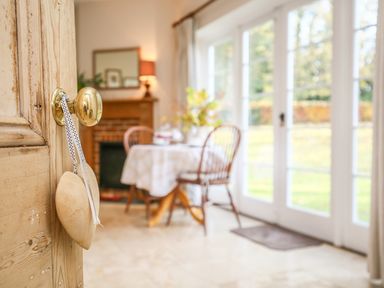 A dining area with a wooden table and chairs near large glass doors at West Lodge in Rockbourne