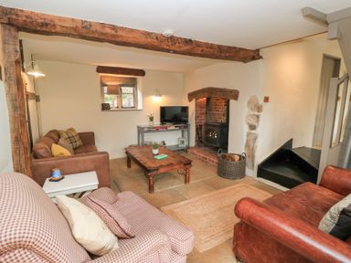 A living room with a wood stove a coffee table and sofas at Cosy Cot in Stapleford