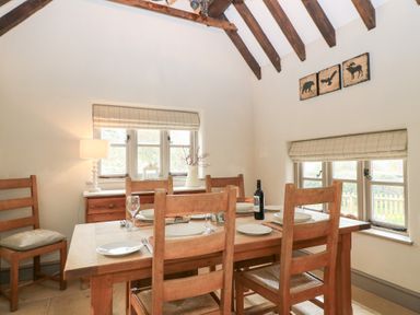 A dining room with a wooden table and chairs set with plates wine bottle and glasses Cosy Cot in Stapleford