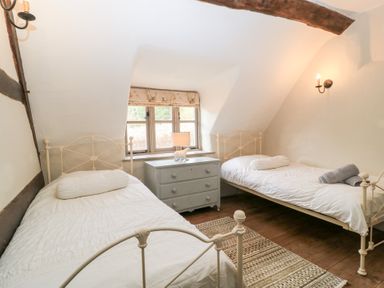 A bedroom with two single beds a chest of drawers and a window at Cosy Cot in Stapleford