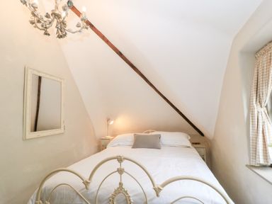A bedroom with a bed a mirror on the wall and a window with curtains at Cosy Cot in Stapleford