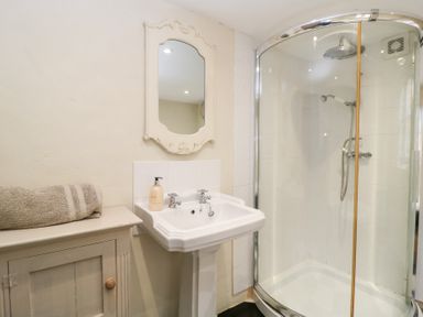 A bathroom with a pedestal sink mirror shower enclosure and a cabinet with a towel on top at Cosy Cot in Stapleford