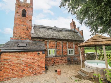 An outdoor area with a brick building and a hot tub at The Shooting Folly in Cheswardine