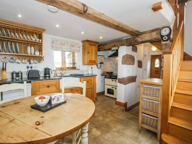A kitchen with wooden cabinets and table at The Shooting Folly in Cheswardine