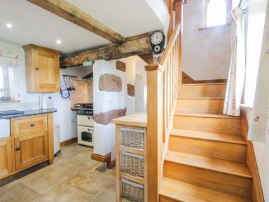 A kitchen with wooden cabinets and stairs at The Shooting Folly in Cheswardine