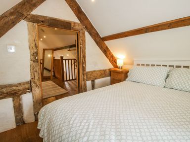 A bedroom with a bed and a door leading to a staircase at The Shooting Folly in Cheswardine