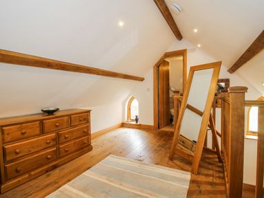 A loft space with a dresser and mirror at The Shooting Folly in Cheswardine