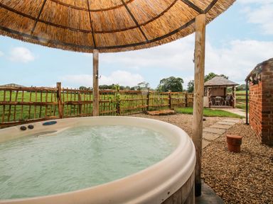 A hot tub with a thatched roof and a garden house at The Shooting Folly in Cheswardine
