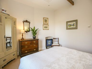 A bedroom with a bed a chest of drawers a wooden chair and a wardrobe at East Lodge in Rockbourne