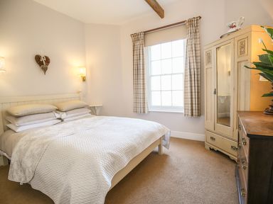 A bedroom with a made bed a window with curtains an armoire and chest of drawers at East Lodge Rockbourne