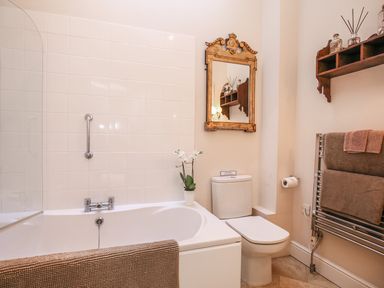 A bathroom with a bathtub a toilet a decorative mirror and towels on a heated rack at East Lodge in Rockbourne