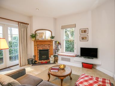 A living room with a fireplace a round wooden coffee table a television and a window seat at East Lodge in Rockbourne