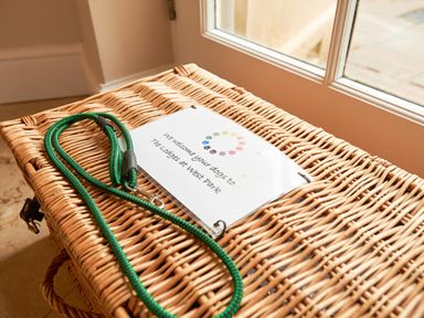 A wicker basket with a green dog leash and a welcome note on it near a glass door at East Lodge in Rockbourne