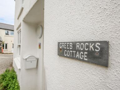 Exterior wall of a white building with a sign reading Greeb Rocks Cottage and a white mailbox at Greeb Rocks Cottage in Marazion