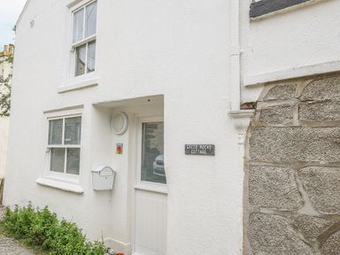 The exterior of a white cottage with windows a door and a mailbox at Greeb Rocks Cottage Marazion