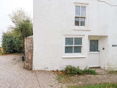 An exterior view of a white cottage with windows and door at Greeb Rocks Cottage Marazion