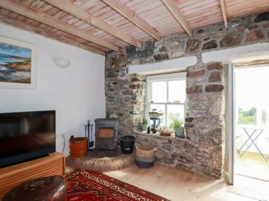A living room with a wood stove and a television at Greeb Rocks Cottage in Marazion