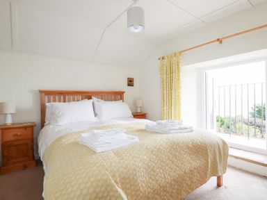 A bedroom with a bed and bedside table at Greeb Rocks Cottage in Marazion