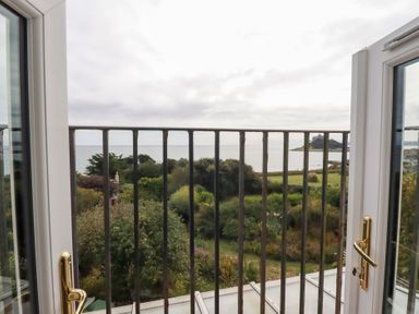 A view from a balcony showing the sea and landscape at Greeb Rocks Cottage in Marazion