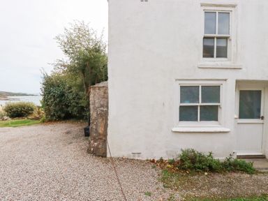 An outdoor view of a house with gravel driveway at Greeb Rocks Cottage in Marazion