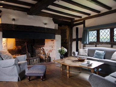 A living room with a fireplace armchairs a sofa a coffee table and a window at The Yeomans House in Bignor