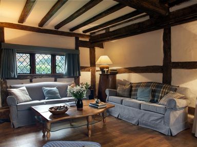 A living room with two sofas a wooden coffee table with flowers and books and a lamp on a side table at The Yeomans House in Bignor