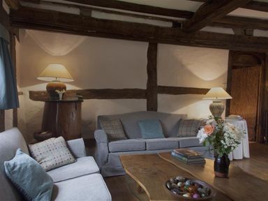 A living room with two sofas a wooden coffee table with books flowers and decorative items and lamps on side tables at The Yeomans House in Bignor