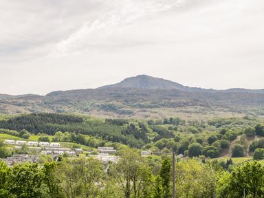 A landscape with houses and trees with hills and a mountain in the background at Arnant in Dolgellau