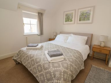 A bedroom with a double bed two bedside tables with lamps and folded towels on the bed at Craigluscar in Newport Pembrokeshire