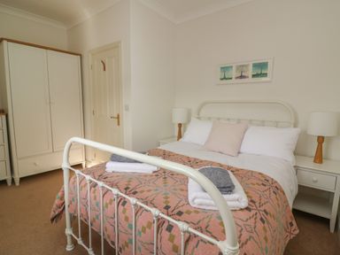 A bedroom with a white metal bed frame bedside tables with lamps a wardrobe and a door at Craigluscar in Newport Pembrokeshire